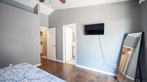A bedroom with a bed, a ceiling fan, a TV, and a mirror. - Cozy Cool 3 Bedrooms Home W~Pool (North Las Vegas)