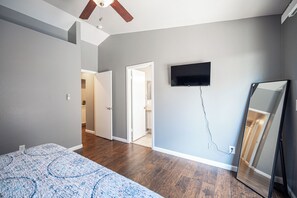 A bedroom with a bed, a ceiling fan, a TV, and a mirror. - Cozy Cool 3 Bedrooms Home W~Pool (North Las Vegas)