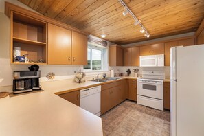 A kitchen with wooden cabinets, a dishwasher, a microwave, an oven, and a refrigerator. - New Listing! Explore Big Sky, Hike + Ski (Big Sky)