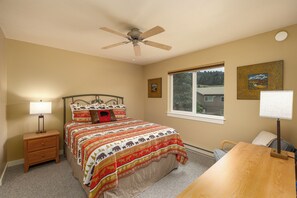 A bedroom with a bed, a nightstand, a desk, a chair, a window, and a ceiling fan. - New Listing! Explore Big Sky, Hike + Ski (Big Sky)