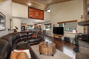 A spacious living room with a large L-shaped leather sofa, a wooden coffee table, and a television.