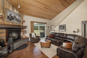 A living room with a fireplace, leather sofa, and a large window.