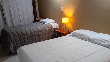 Een hotelkamer met twee bedden, een nachtkastje met een lamp en een gordijn.