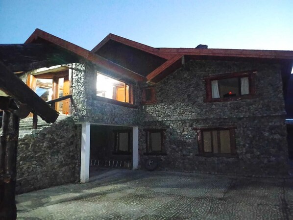Un edificio de piedra con techo inclinado, varias ventanas y una escalera visible que lleva a un nivel superior.