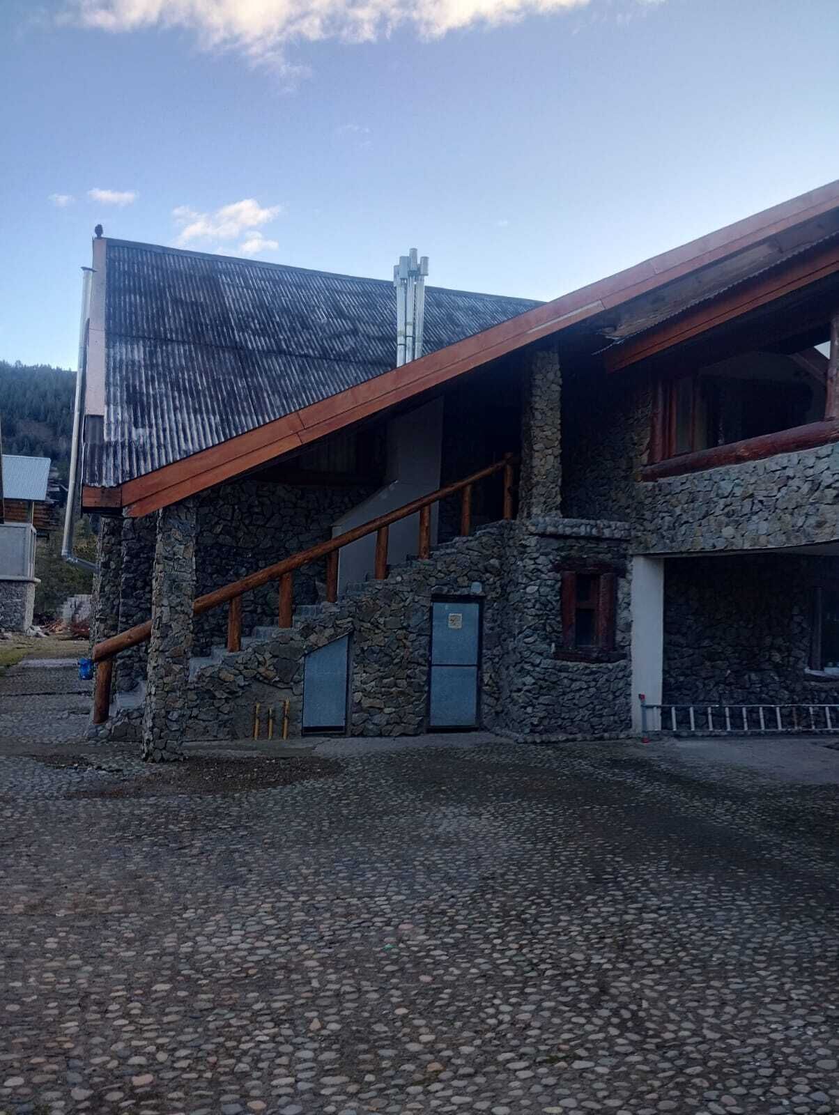 A building with a stone facade, a sloped roof, and a wooden staircase leading to an upper level.