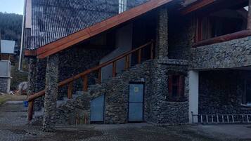 A building with a stone facade, a sloped roof, and a wooden staircase leading to an upper level.