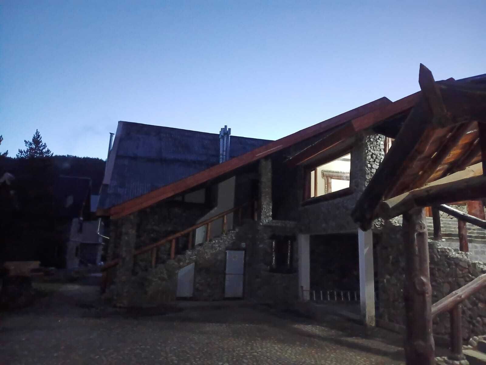 Un edificio de piedra con escalera de madera y techo de metal.