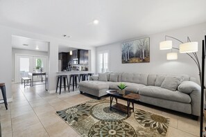 Ein modernes Wohnzimmer mit einem grauen Ecksofa, einem Couchtisch und einem gemusterten Teppich.