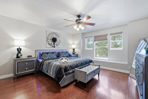 A bedroom with a bed, bedside tables, a ceiling fan, and windows. - Figaro - A Birdy Vacation Rental (San Antonio)
