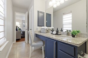 A bathroom with a large mirror, a sink, and a vanity with cabinets. - Figaro - A Birdy Vacation Rental (San Antonio)