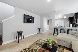 A modern living room with a flat-screen TV, a sofa, and a coffee table with a plant. - Figaro - A Birdy Vacation Rental (San Antonio)