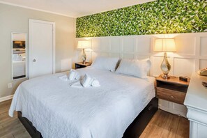 A hotel room with a large bed, two bedside tables, a mirror, and a wall with a leafy pattern. - Relaxing Place to Stay at Ocean Creek with Pools (Myrtle Beach)