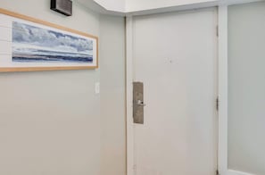 A closed door with a metal handle, a framed picture of a seascape on the wall, and a light switch. - Relaxing Place to Stay at Ocean Creek with Pools (Myrtle Beach)