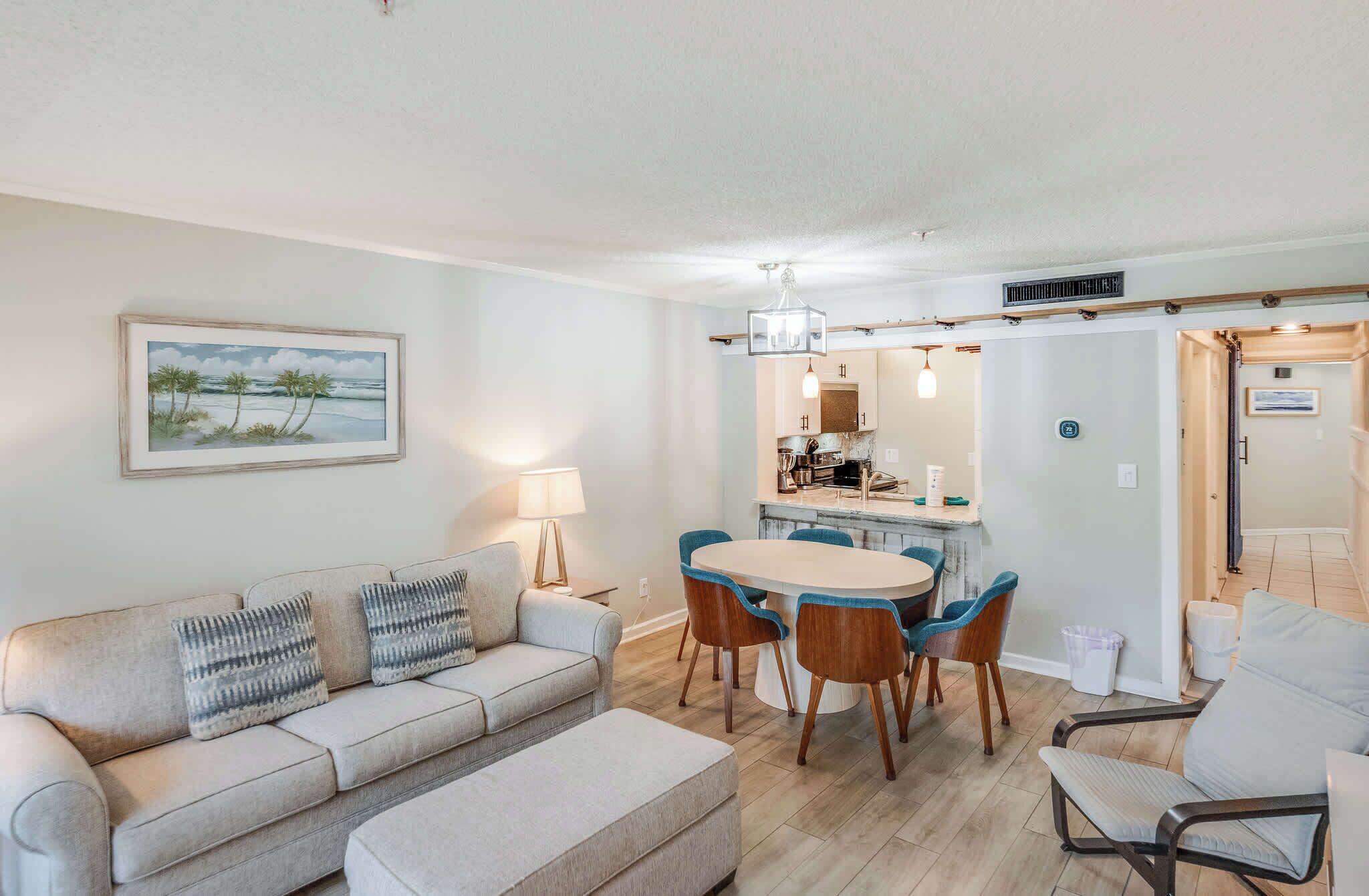 Un salon comprenant un canapé, un pouf et un coin repas avec des chaises et une table.