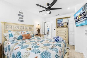 A bedroom with a bed, a ceiling fan, a dresser, and a wall-mounted TV. - Beachside Escape with Pool & Steps to Crescent Beach - Aloha Kai #51 (Siesta Key)