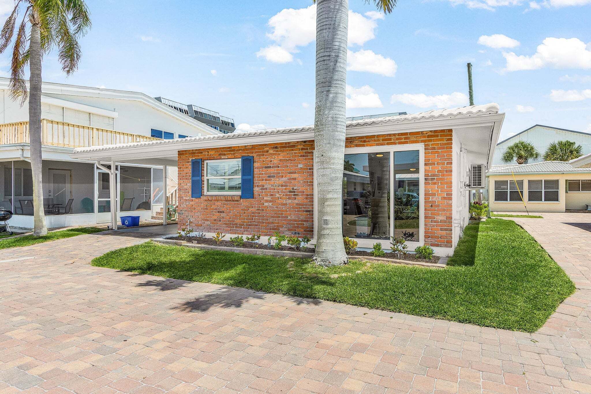 A modern house with a brick exterior, a covered patio, and a well-maintained lawn.