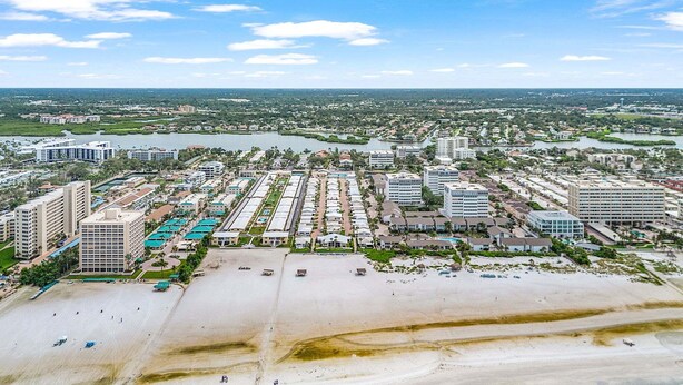 Oversigtsbillede af en kystresort med ejendomme ud til stranden, en lysthavn og en strand.