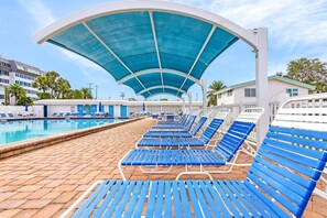 A pool area with blue lounge chairs and a covered walkway. - Beachside Escape with Pool & Steps to Crescent Beach - Aloha Kai #51 (Siesta Key)