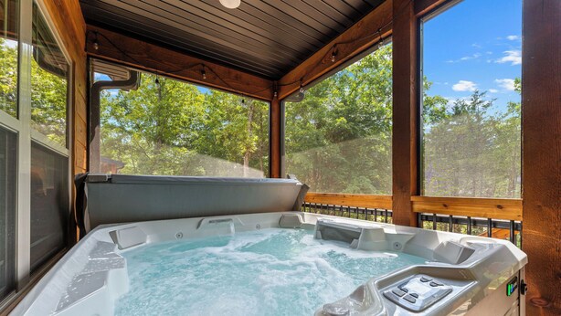 A hot tub in a wooden cabin with a view of trees. - Rustic Log Cabin, 1-Min Walk to Lazy River — Hot Tub, Sleeps 6, Resort Pools (Hollister)