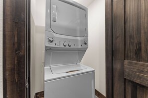 A front-loading washer and dryer in a laundry room with wooden doors and white walls. - Resort Cabin: Lazy River, Pickleball, Pools (Hollister)