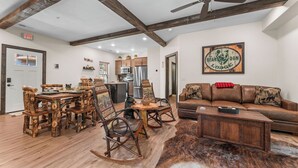 A rustic interior with a dining area, a sofa, and a bear-themed wall art. - Rustic Log Cabin, 1-Min Walk to Lazy River — Hot Tub, Sleeps 6, Resort Pools (Hollister)