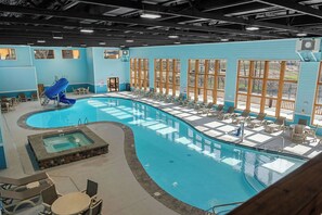 Una piscina interior con tobogán, sillas de descanso y zona de hidromasaje.