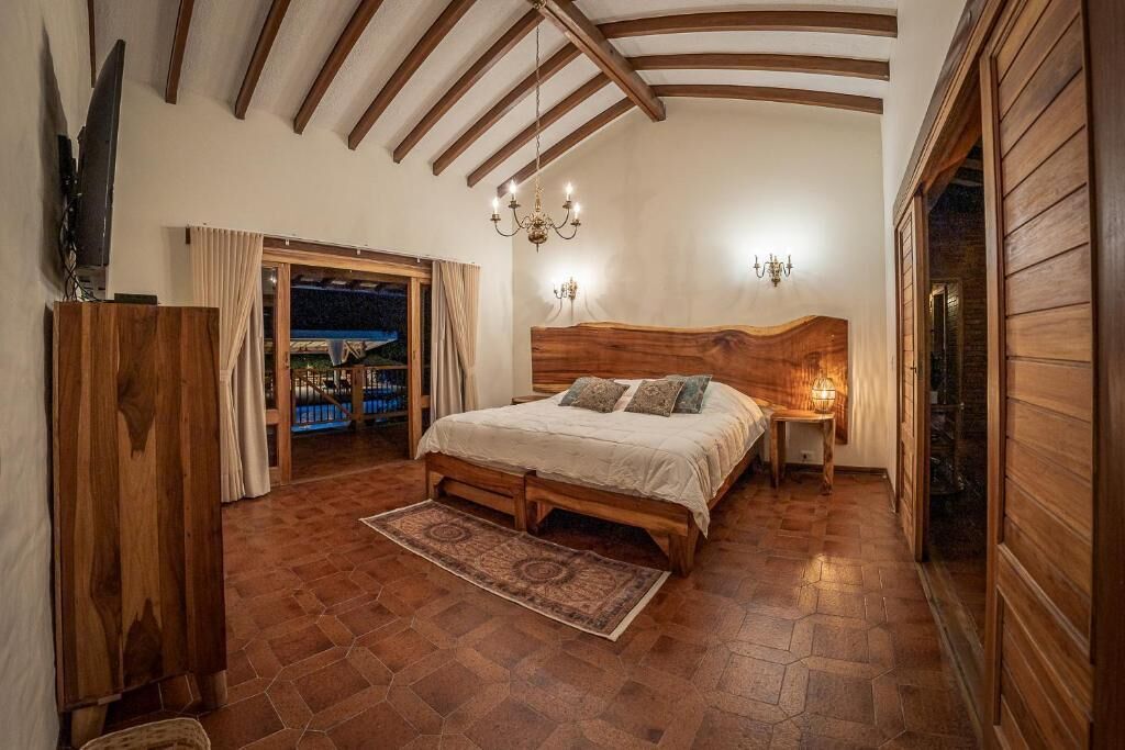 Un dormitorio con cama de madera, un candelabro y vistas a través de una puerta.