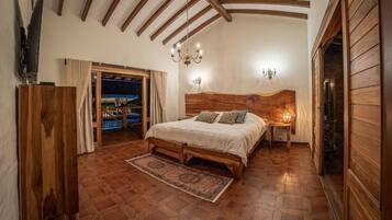 Un dormitorio con cama de madera, un candelabro y vistas a través de una puerta.