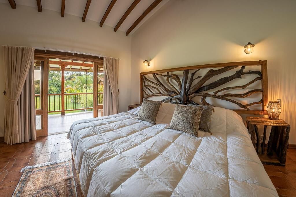 Un dormitorio con una cama grande, cabecera de madera, mesita de noche y vista a un balcón.