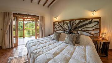 Un dormitorio con una cama grande, cabecera de madera, mesita de noche y vista a un balcón.