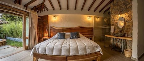 Un dormitorio con una cama grande, vigas de madera, paredes de piedra y un lavamanos de piedra.