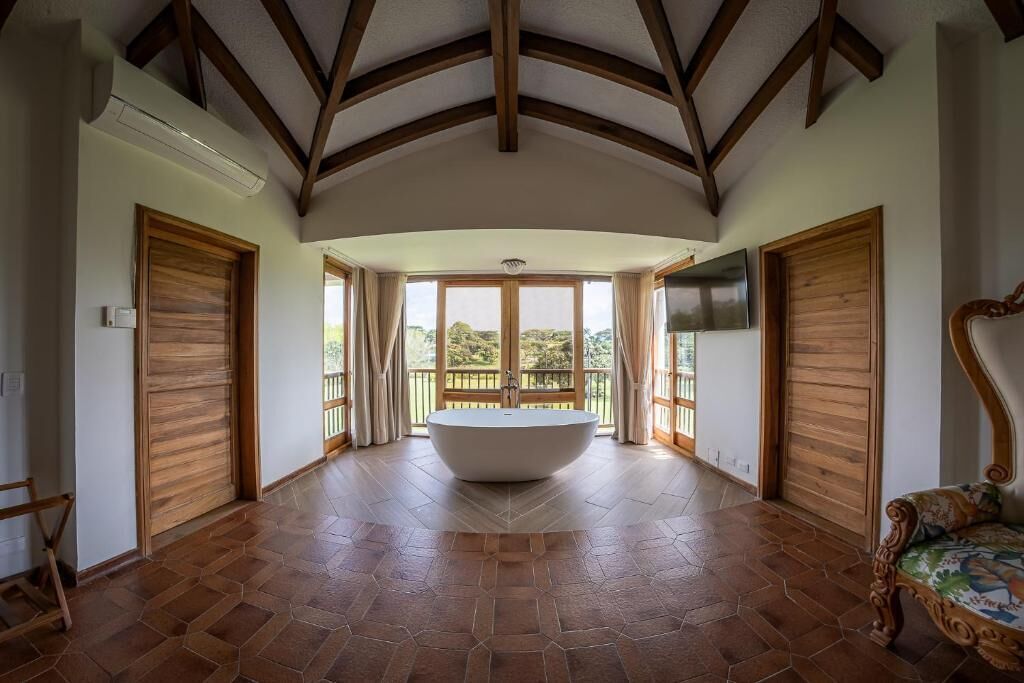 Un baño espacioso con una bañera independiente, puertas de madera y vistas al exterior.