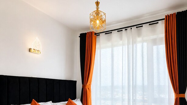 A hotel room with a bed, curtains, a headboard, and a hanging light fixture. - Luxury one bedroom-Roysambu near CBD (Nairobi)