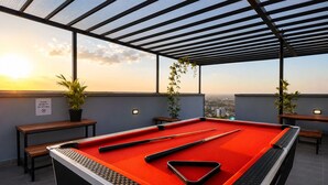 A pool table with pool cues, a red felt surface, and a city view at sunset. - Luxury one bedroom-Roysambu near CBD (Nairobi)