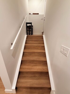 Un escalier en bois, avec des murs blancs et une main courante.