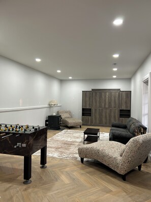 A modern living room with a foosball table, a sofa, a coffee table, and a large wardrobe. - Wonderful 3-bedroom lakefront home with a private dock on lake Loch Lomond (Bella Vista)