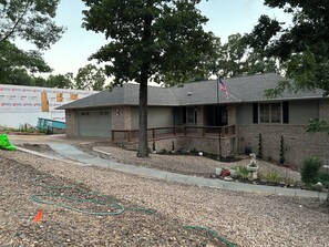A residential house with a brick exterior, a front porch, and a flagpole. - Wonderful 3-bedroom lakefront home with a private dock on lake Loch Lomond (Bella Vista)