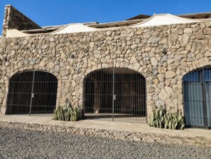 Ein Gebäude mit einer Stein-Fassade, drei Rundbogenfenstern und einer Schotterauffahrt.