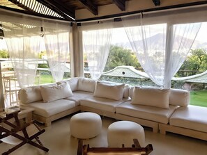 Ein modernes Wohnzimmer mit einer Eckcouch, Poufs und einem Holztisch.