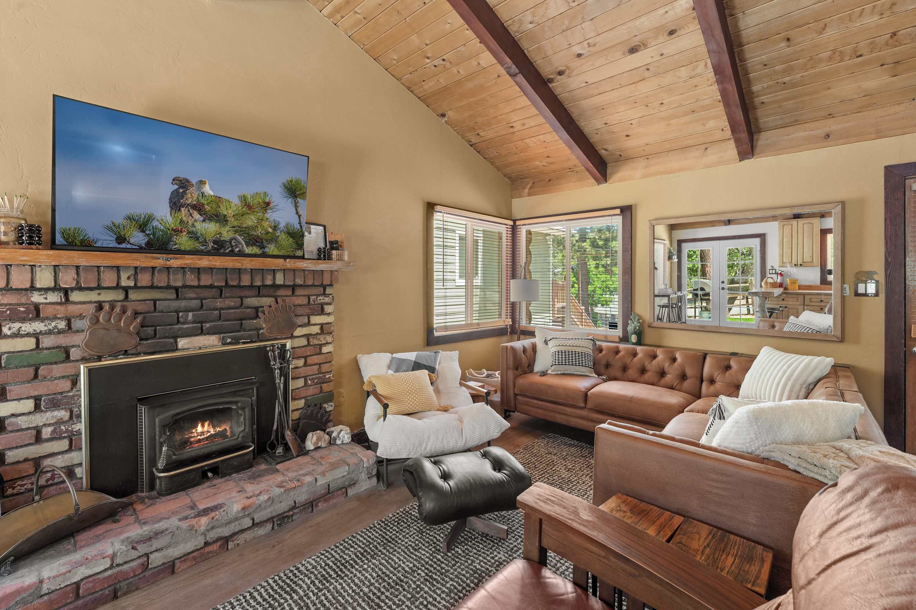 A living room with a fireplace, leather sofa, and a television mounted above it.