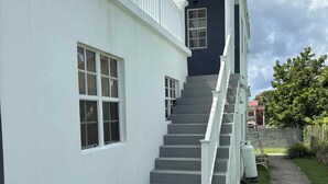 Ein zweistöckiges Haus mit weißer Fassade, einer dunkelblauen Akzentwand und einer Treppe, die zum oberen Stockwerk führt.