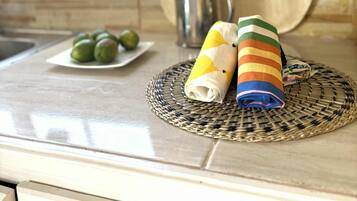 Un piano di lavoro in cucina con un sottobicchiere intrecciato, un piatto di lime e asciugamani arrotolati.