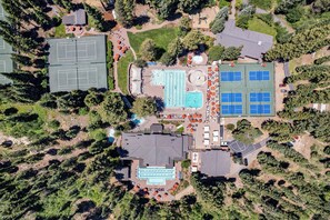 Ein Luftbild eines Sportkomplexes mit Tennisplätzen, einem Schwimmbad und einem überdachten Bereich mit Solaranlagen.