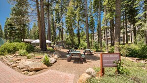 A campground with picnic tables, a sign indicating group BBQ sites, and a paved walkway. - The Nest at Northstar by Tahoe Getaways - 3BR Walk to Northstar w HOA & Ski Shuttle! (Truckee)
