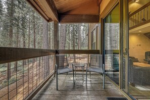 Eine Holzterrasse mit Glasgeländer mit Blick auf einen Wald.