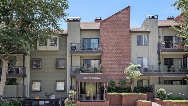A multi-story residential building with a brick facade, balconies, and a ground-level entrance with a sign. - Heart of Pasadena - Walkable/Bikeable to hospitals, Old Town and Caltech/PCC (Pasadena)
