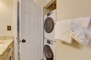 Una sala de lavandería con dos lavadoras de carga frontal y una toalla blanca colgada en la pared.