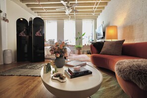 A living room with a round coffee table, books, a vase with flowers, a sofa, and a TV. - Cozy 1-bedroom apartment in nice Brooklyn with AC (Brooklyn)