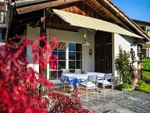 A rustic outdoor seating area with a table and chairs, a hanging light fixture, and a statue. - Bolzbach mit Seeanstoss by Interhome (Altdorf UR)