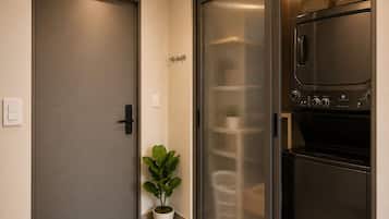 Una cocina moderna con horno empotrado y microondas, una puerta corrediza de vidrio y una planta en maceta.